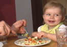 Kleinkind isst mit den Fingern vom Teller