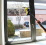 Eine Person wischt ein Fenster mit einer Teleskopstange und einem Akkusauger