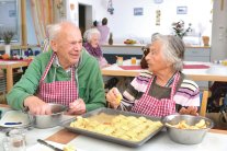 Zwei Senioren belegen einen Apfelkuchen