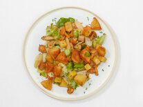 Gröstl mit Kartoffel, Pilzen und Gemüse auf einem weißen Teller