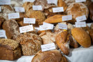 Viele verschiedene Brotsorten auf einem Tisch mit Schild mit den Namen der Brote