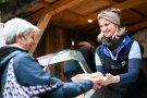 Verkäuferin übergibt einer Dame eine Krustensemmel mit warmer, geräuchrter Forelle