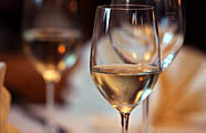 Gefülltes Weißweinglas am gedeckten Tisch