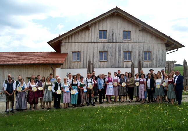 Alle Gewinner des Goldenen Gockels posieren für ein Gruppenfoto mit Ministerin Michaela Kaniber vor einem Haus. 