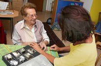 Seniorin zeigt Betreuerin ein Fotoalbum