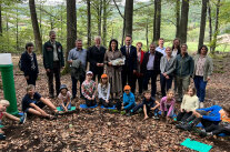 Michaela Kaniber im Wald mit der am Boden sitzenden Ferienspaß-Kindergruppe