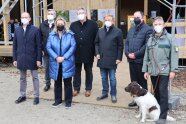 Menschengruppe mit Mund-Nasen-Schutz und einem Hund vor einem Gebäude